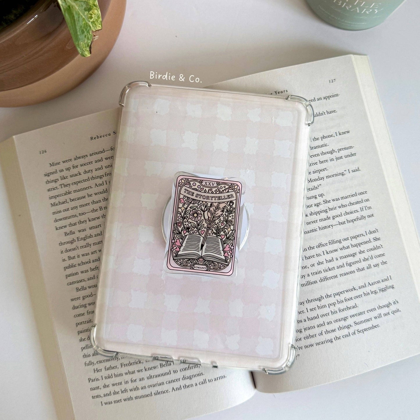 Decorative box with a decorative item on an open book next to a candle and plant