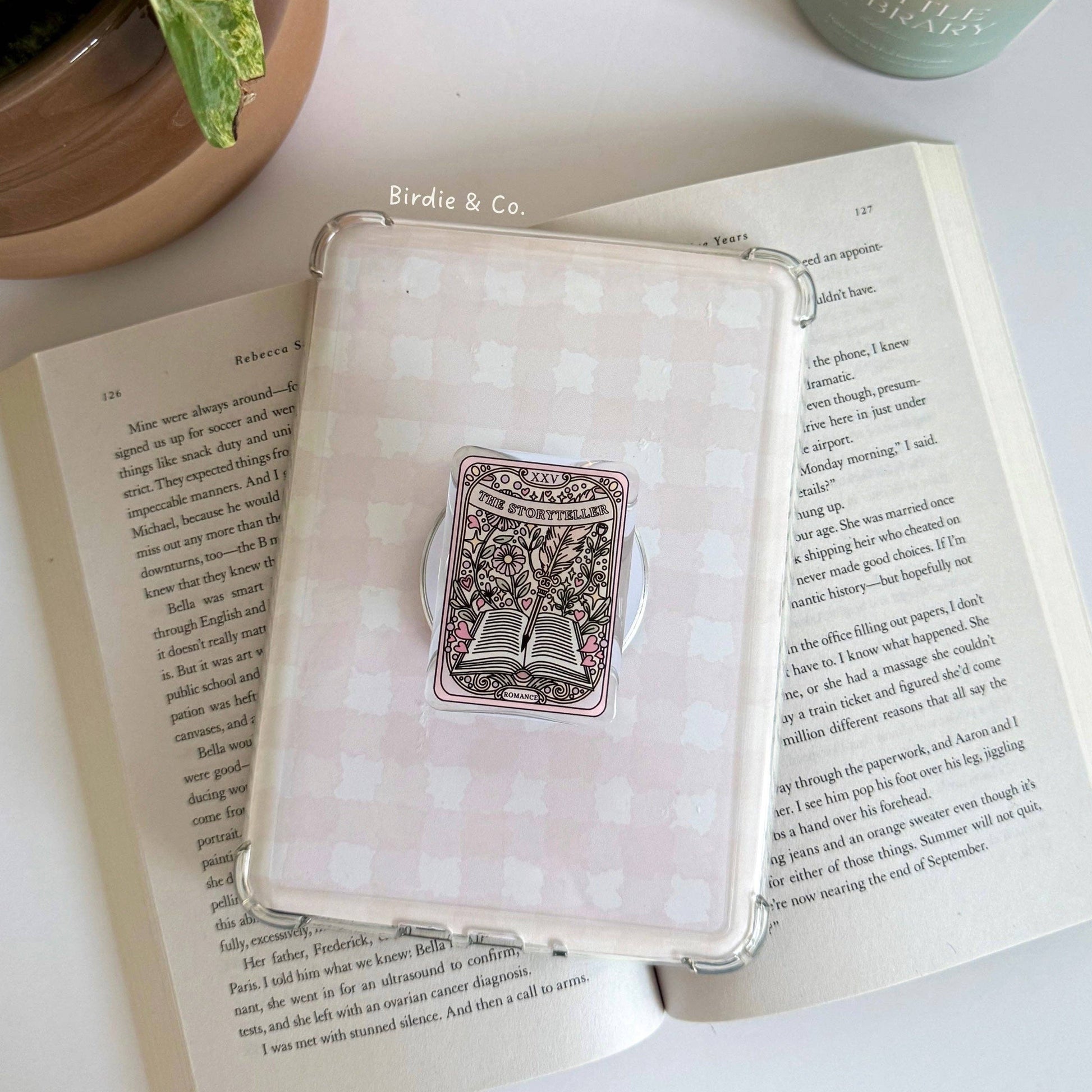 Decorative box with a decorative item on an open book next to a candle and plant
